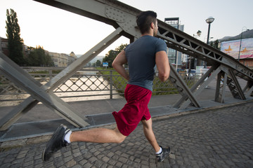 man jogging across the bridge at sunny morning