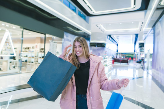 A smiling girl with shopping in the hands of a genuine shopping mall. Shopping concept.