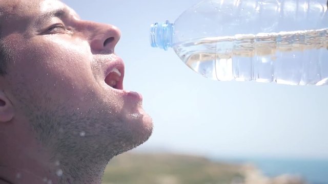 A man with a bristle quenches his thirst, he drinks water from a bottle in large sips. HD, 1920x1080, slow motion
