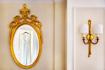 Elegant wedding dress hanging on the door and reflecting in the mirror