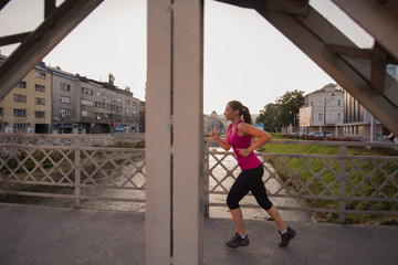 Fototapeta na wymiar woman jogging across the bridge at sunny morning