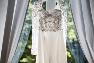 Wedding dress hanging on the window in the room