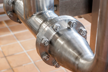 Connection of stainless steel pipes with bolts. Brilliant surfaces.