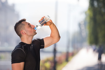 man drinking water from a bottle after jogging