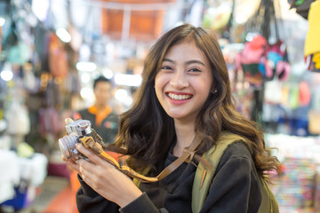 Portrait of Happy Traveler Woman in Market. Asian women Hold Retro Camera for Take Photo, People...