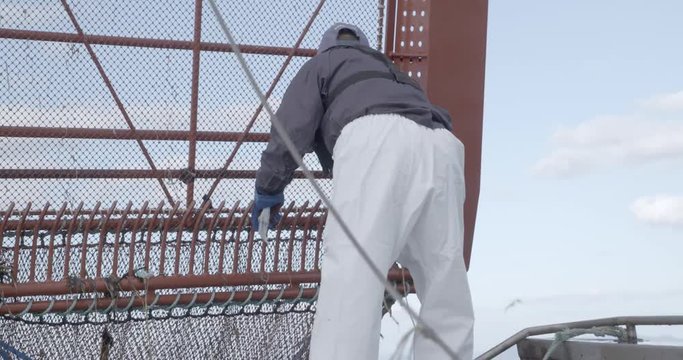 漁船で網にかかったゴミをとる漁師