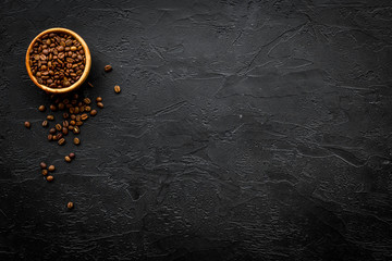 Coffee background. Roasted beans in bowl on black table top view copyspace