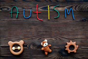 Diseases. Infantile autism. Word with colored letters near toys on dark wooden background top view background top view copyspace