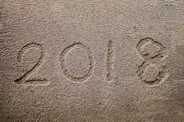 Year 2018 on sand beach background