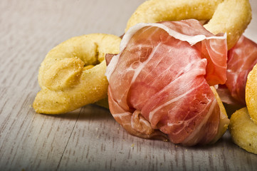 Taralli on the white wood table with sliced ham