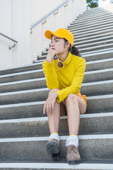 Portrait of beautiful asian woman in yellow cloths,Hipsters girl wear yellow hat sit on stair for take a picture,Thailand people