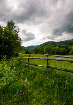 wooden fence on a rural meadow in mountains. lovely agriculture scenery on a cloudy summer day