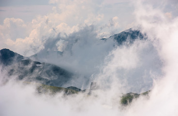 cloud formation in mountains on high altitude. spectacular natural phenomenon in summer. lovely weather background of hills with snow and grass