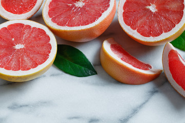 View from above on slices and halves of grapefruits on a white marble table.
