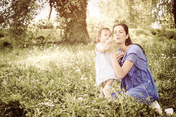 Pregnant mother playing with little daughter in park. On the move.