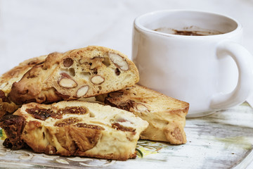 White mug with black tea and heap of biscotti cookies on light background. Very testy biscotti or cantucci on wooden board.