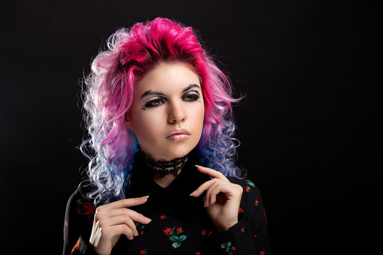 Glamorous portrait of a girl with pink hair and bright makeup on black isolated background close-up