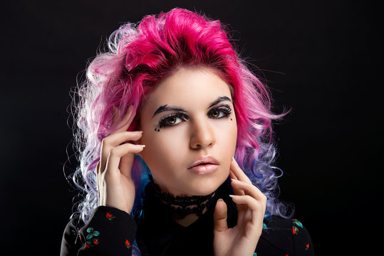 Glamorous portrait of a girl with pink hair and bright makeup on black isolated background close-up
