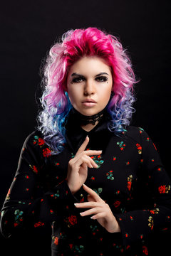 Glamorous girl with pink hair and bright make-up in vintage dress with roses on a black isolated background