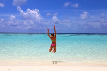 Fototapeta na wymiar Jumping happy girl on the beach, fit sporty healthy sexy body in bikini, woman enjoys wind, freedom, vacation