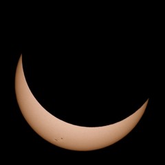 The Sun partially eclipsed by the moon during the total solar eclipse on 2017-AUG-21. Several sunspots are visible on its surface.