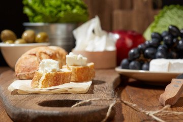 Cheese, vegetables, fruits and spices. Bread, olives and crackers. Mediterranean diet and cuisine. Dark background.