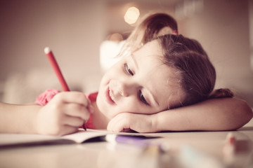 Cute little girl drawing something on paper. Close up.