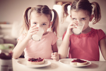 Obraz na płótnie Canvas Girls eating breakfast. Drinking milk.