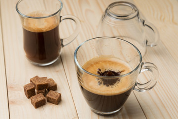 hot coffee with foam in a glass on a wooden table, dropping drop, a splash of coffee in a glass, brown sugar