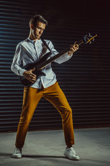 Rock guitarist is playing guitar in the dark studio.