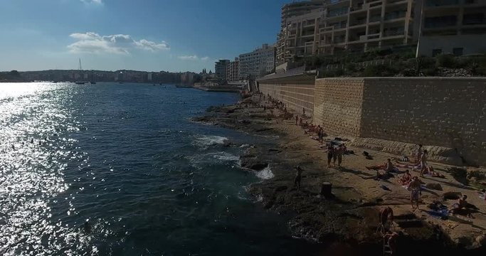 MALTA – AUGUST 2016 : Aerial shot over Sliema beach on a sunny day with people and cityscape in view