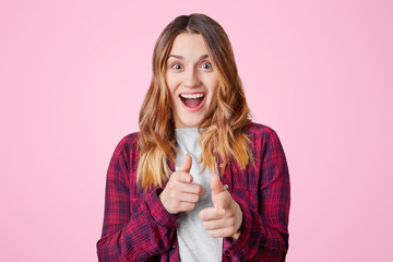 Excited overjoyed female model with dark eyes, pure skin and straight hair, opens mouth in joy and...