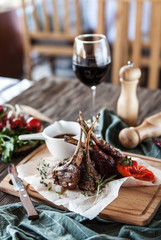 beautiful serve entrecote - lamb on bone with pepper and tomato sauce on a wooden board and with a glass of wine - 185759293