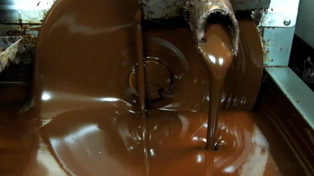 a machine mixes dark chocolate at a factory