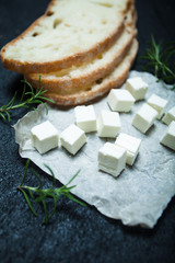 Traditional Greek feta cheese, bread and rosemary on a black background.