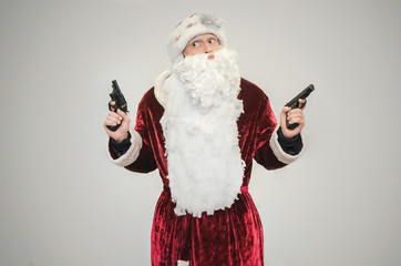 Bad angry Santa Claus with guns in hands isolated on gray background.