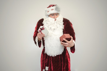 Shocked Santa Claus holds in hands open Christmas present box isolated on gray background.