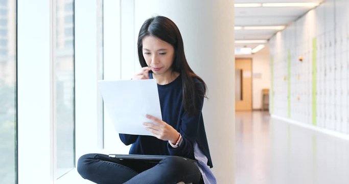 Student studying on paper note inside university campus, reading and revise on note, prepare for exam