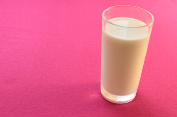 a glass of milk on a pink background