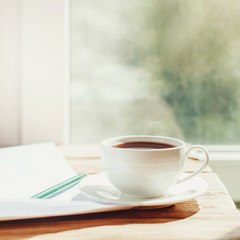 cup of coffee on old wooden desk. Simple workspace or coffee break in morning/ selective focus