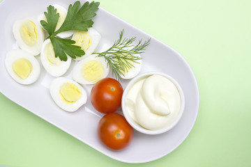 Overhead photo of vegetable salad with boiled quail egg, dill, fresh tomato and lettuce on white porcelain plate. A served salad photo from above, sliced boiled eggs, dill. I like Healthy lifestyle.