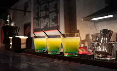 three glasses of cocktails are on the bar