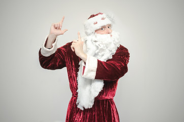 Santa Claus showing on copy space by his hand isolated on gray background.