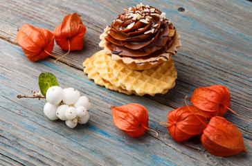 Fototapeta premium Sweet waffle, cake with cream and physalis on a wooden background