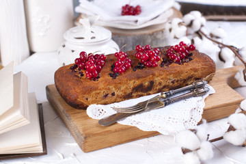 cupcake with red currant on a wooden board and white background, cotton flowers