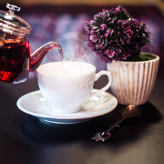 Fruit tea pouring to a white elegant cup, purple background, vintage spoon