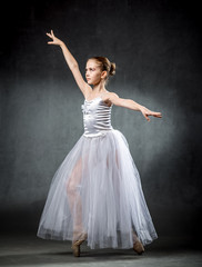 Fototapeta premium Ballet. Image of a flexible cute ballerina dancing in the studio. Beautiful young dancer. A ballerina is posing.