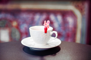 elegant shape white cup with Love clip on dark table and oriental background