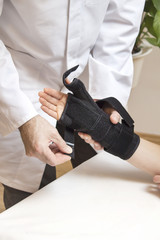 Lekarz ortopeda zakłada stabilizator na dłoń kobiety. - obrazy, fototapety, plakaty
