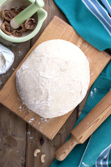 dough on a wooden board and a background of wood, green towel and flour